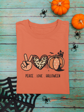 Load image into Gallery viewer, Orange t-shrit with words below emoji symbols consisting of polka dot peace hand, animal print heart and pattern polka dot pumpkin with witch hat and haunted house shiloette. words below saying peace. love. hallowween